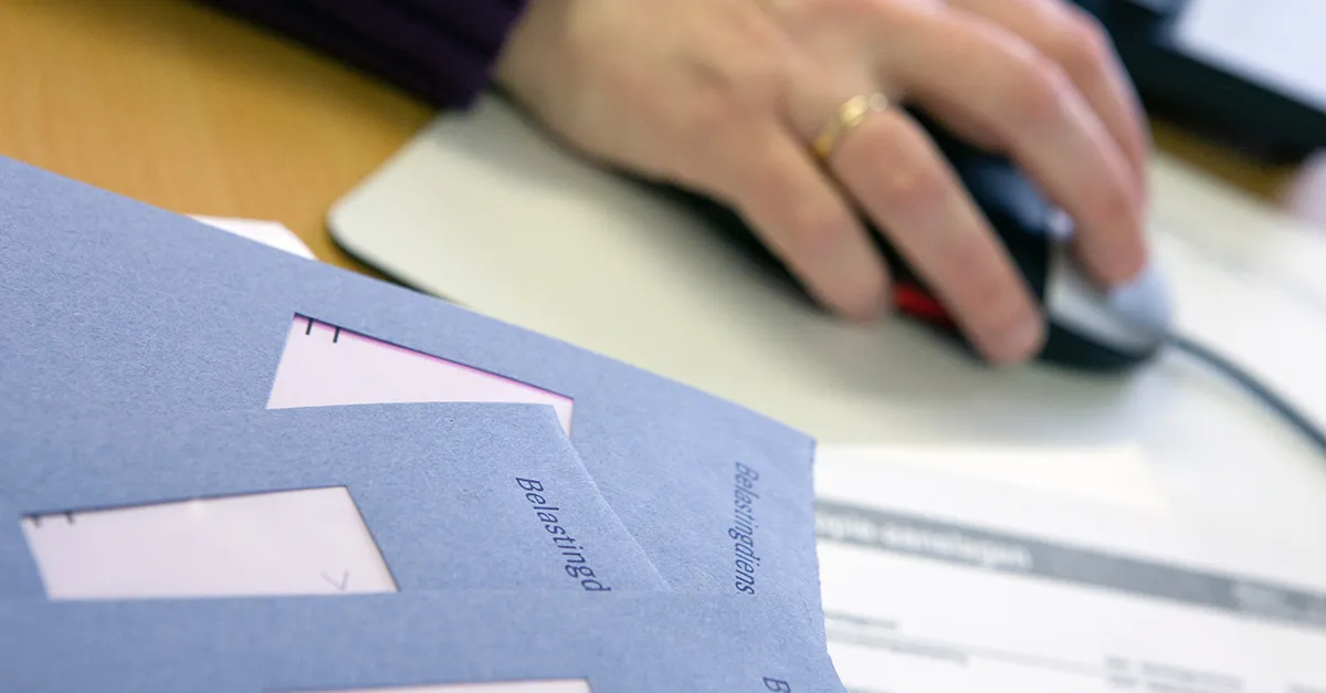 Close-up of a person using a computer mouse next to tax documents and envelopes.