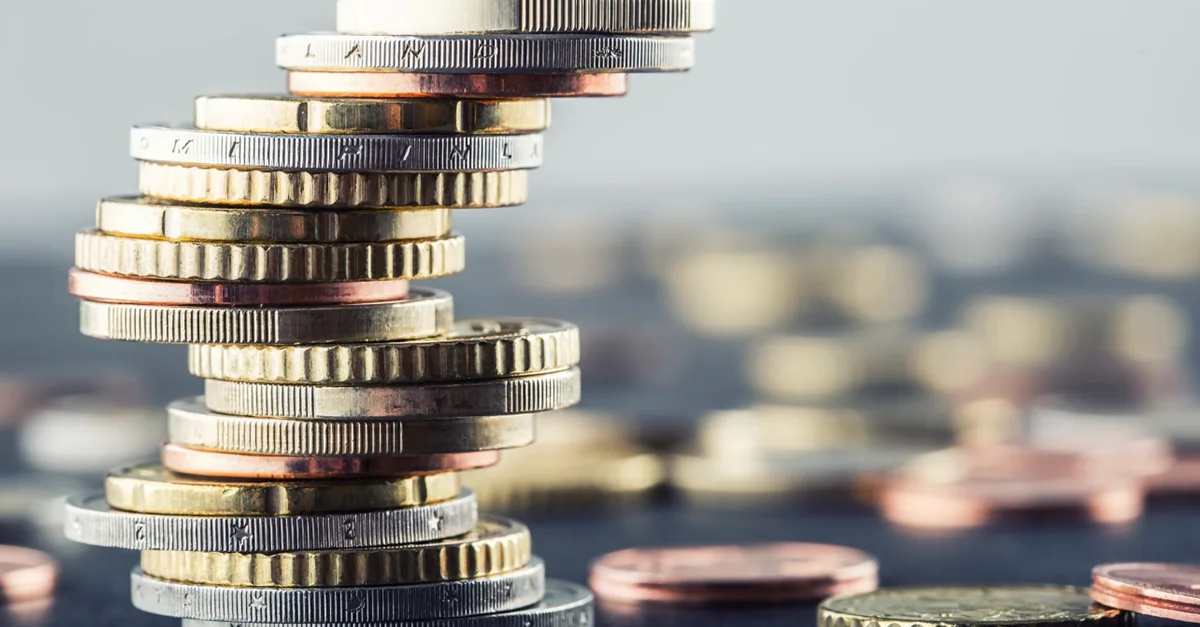 A tall, uneven stack of assorted coins arranged on a surface, symbolizing savings, budgeting, or financial growth.