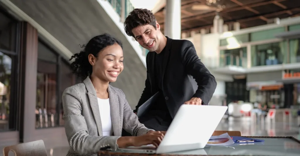 A salary benchmarking expert evaluating a salary benchmarking tool on a laptop with their colleague.