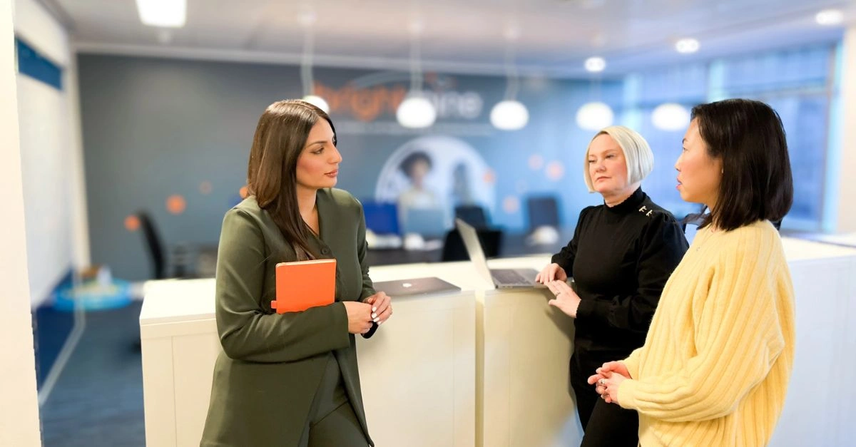 Three female HR specialists talking in the Brightmine office
