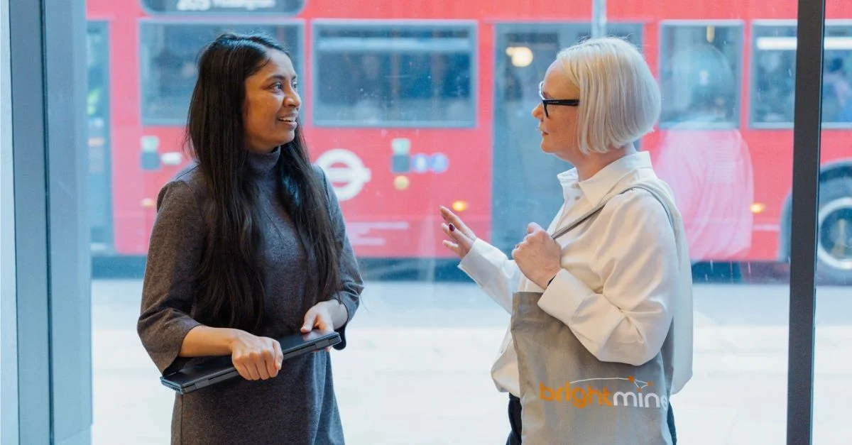 Two female colleagues talking in a London office lobby