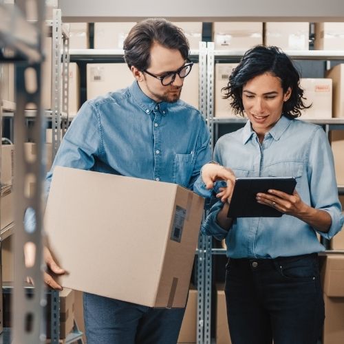 Two colleagues reviewing HR paperwork in a warehouse
