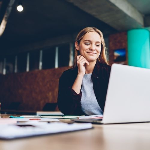 Young female HR manager smiling at laptop.