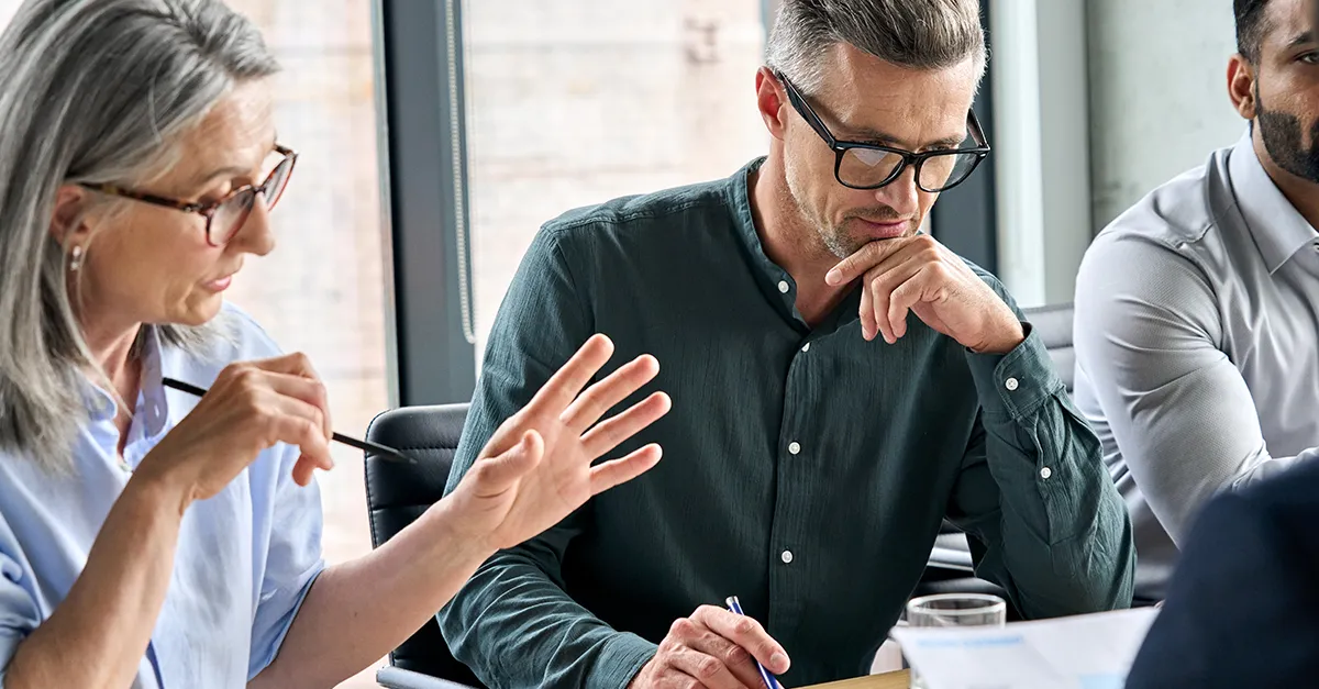 Group of colleagues engaged in a discussion around a table during a meeting.