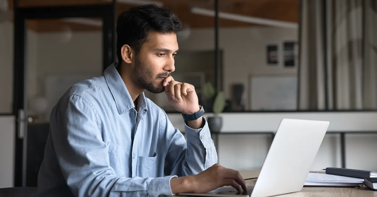 Person working on a laptop at a desk in a modern office setting.