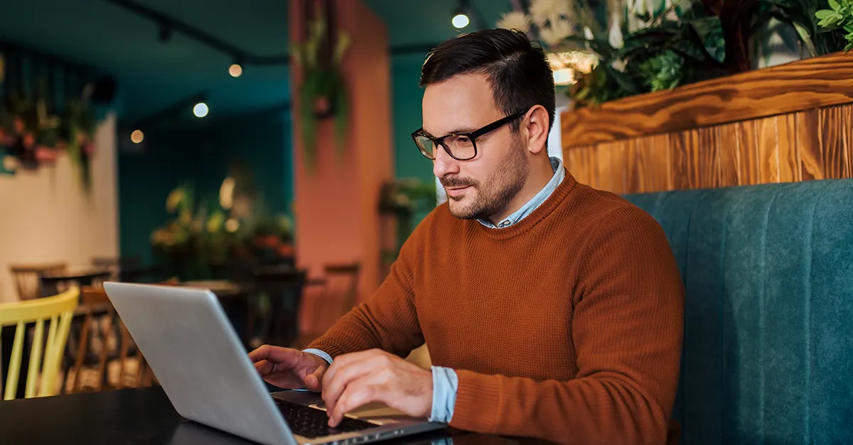 Person typing on a laptop while seated in a cafe-style workspace.