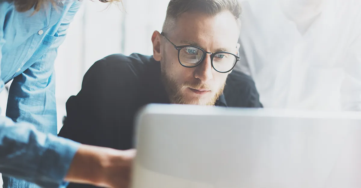 Team members collaborating on a project while working together at a computer workstation.