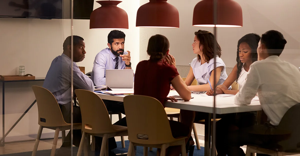 A group of colleagues collaborating around a conference table in a modern meeting room.