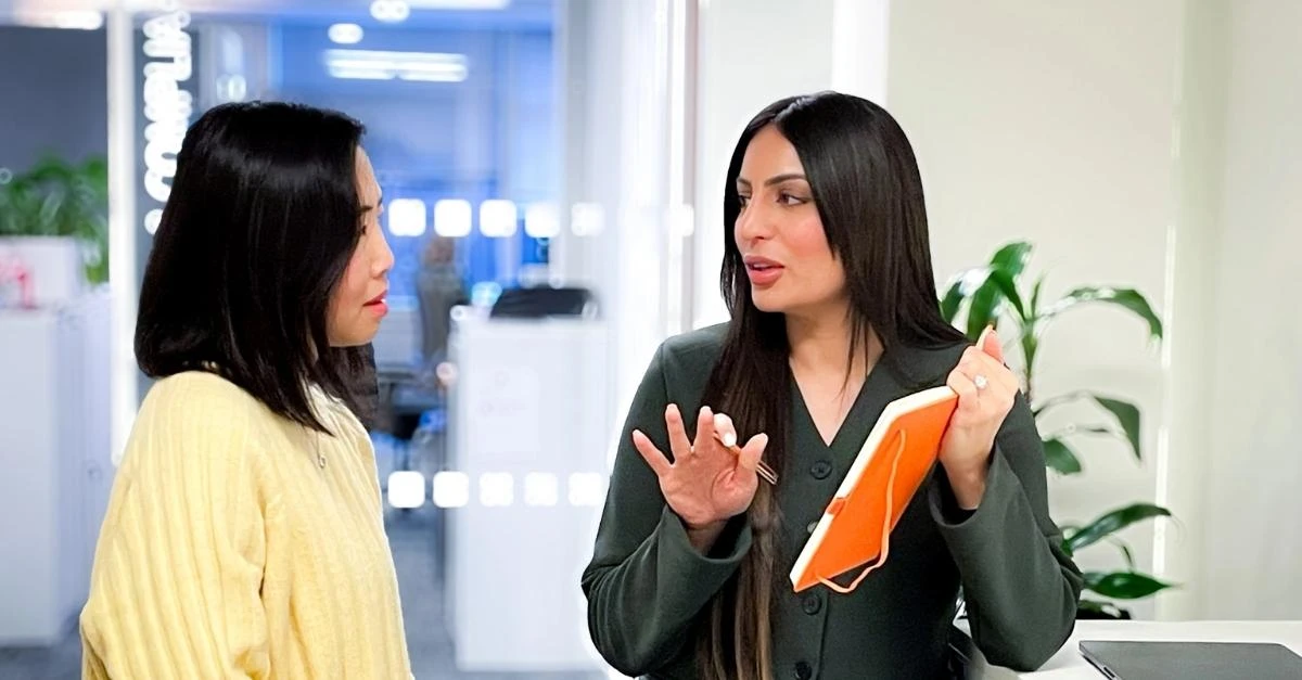 Two female HR professionals discussing notes in an office