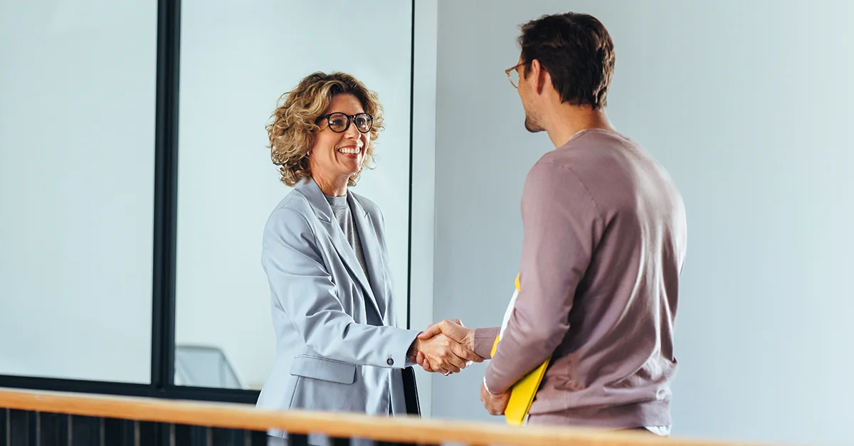 Two individuals shaking hands in an indoor setting.