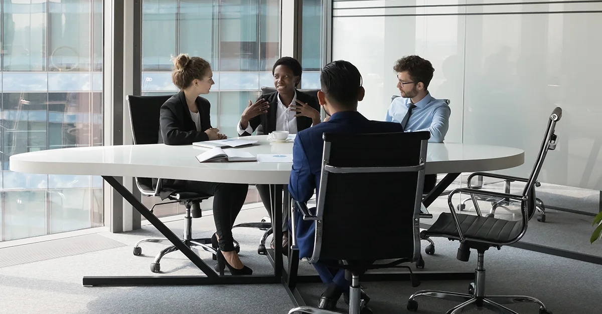 Group of individuals seated around a conference table during a meeting in a modern office.