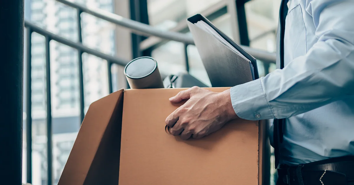Person carrying a cardboard box in an office area