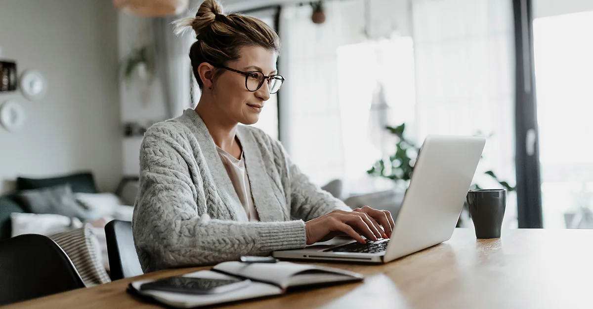 Woman working on a laptop at a desk at home