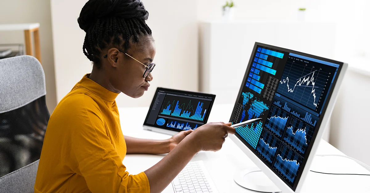 Analyst reviewing charts and data on multiple screens