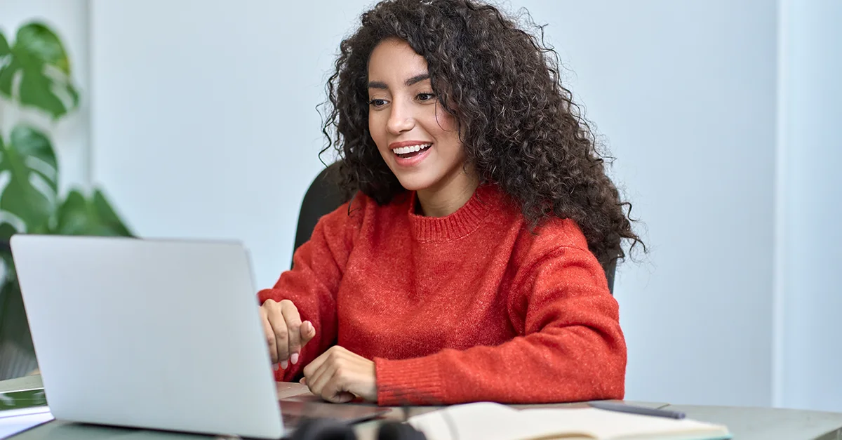 Woman smiling while working on a laptop