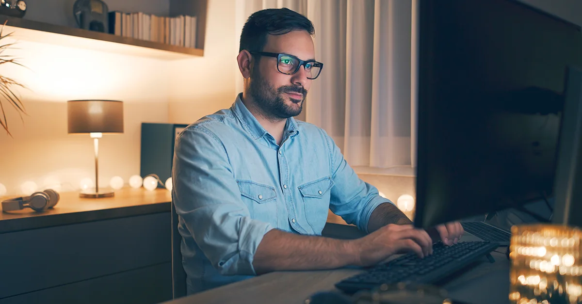 Man working at a computer in a softly lit home office