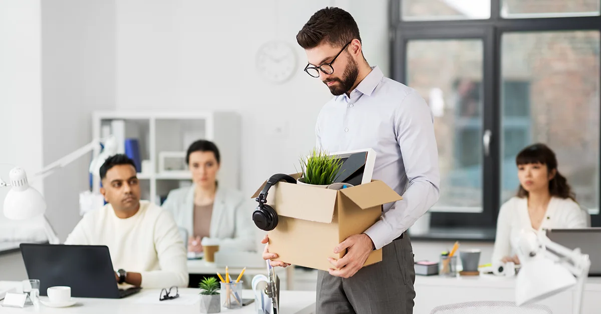Person holding a box with office items in a shared office workspace