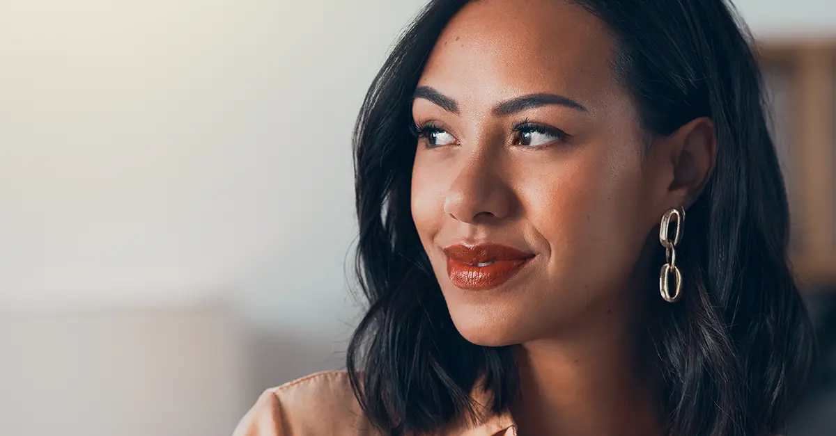 Close-up of a person looking to the side wearing earrings in a softly lit indoor setting