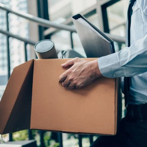 Employee, who was just subject to a layoff, carrying his personal items out of the office in a box.