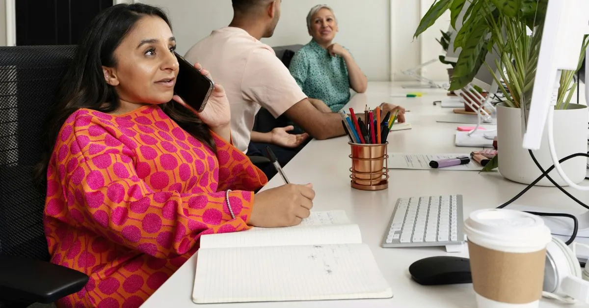 Woman in office on phone writing in notepad