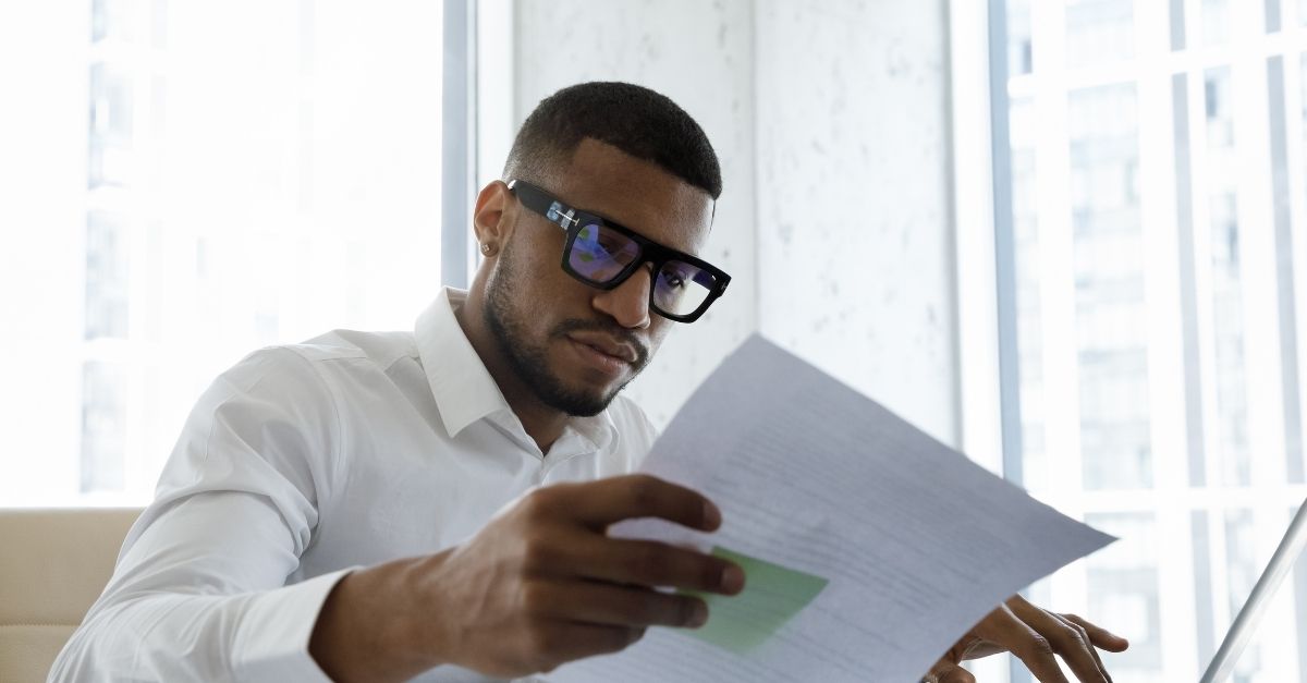 male HR professional reviewing paperwork at desk with laptop