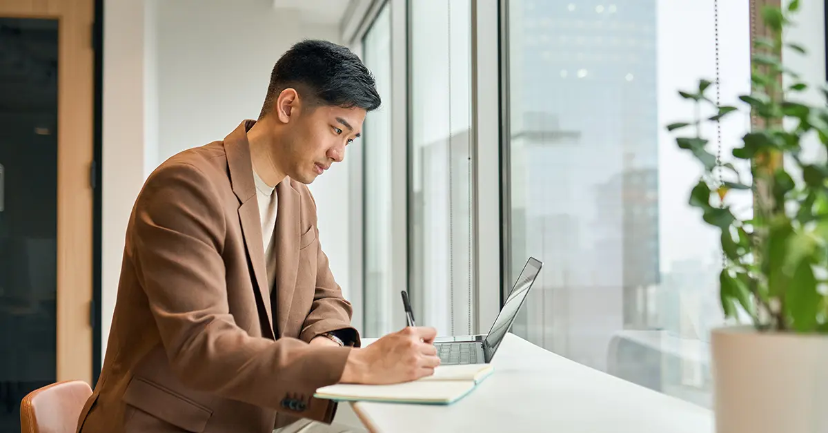 Brightmine office worker taking notes from laptop