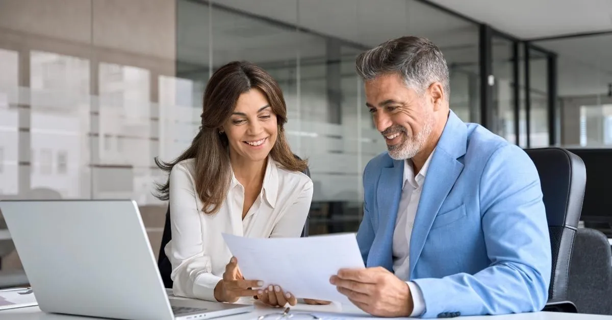 Male and female HR colleagues reviewing paperwork in an office