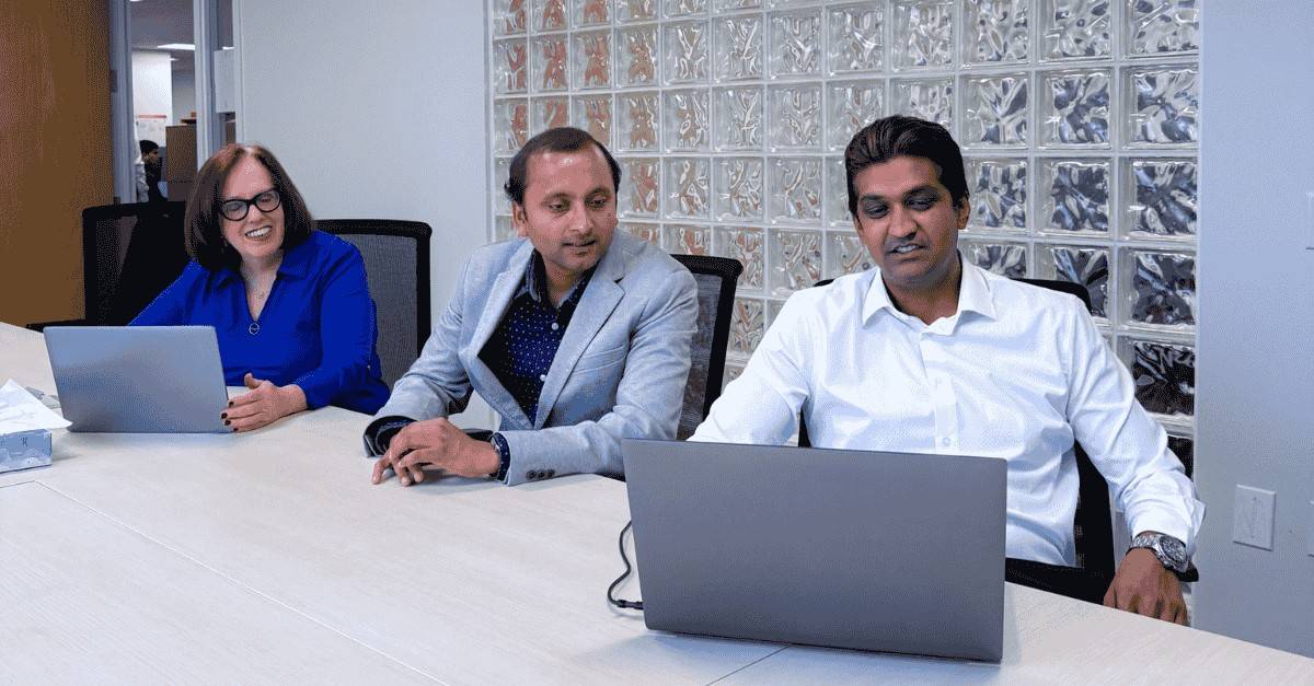 Brightmine workers at desk with laptops