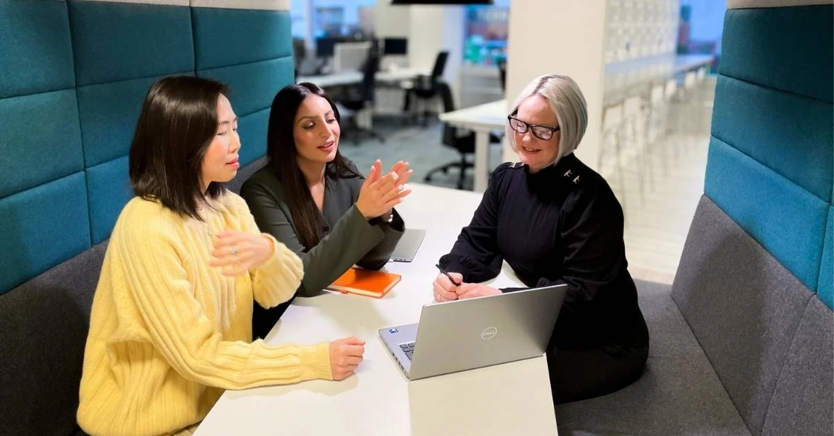 Three female reward specialists discussing pay data from Brightmine