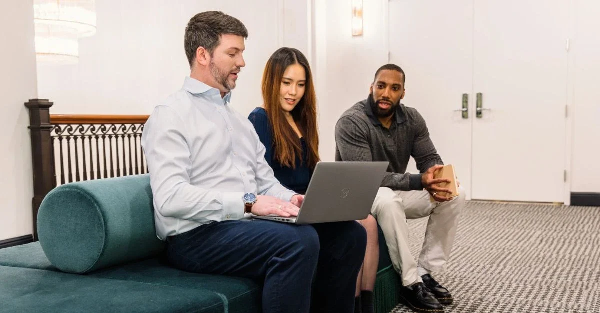 drie collega's die achter een laptop iets doornemen