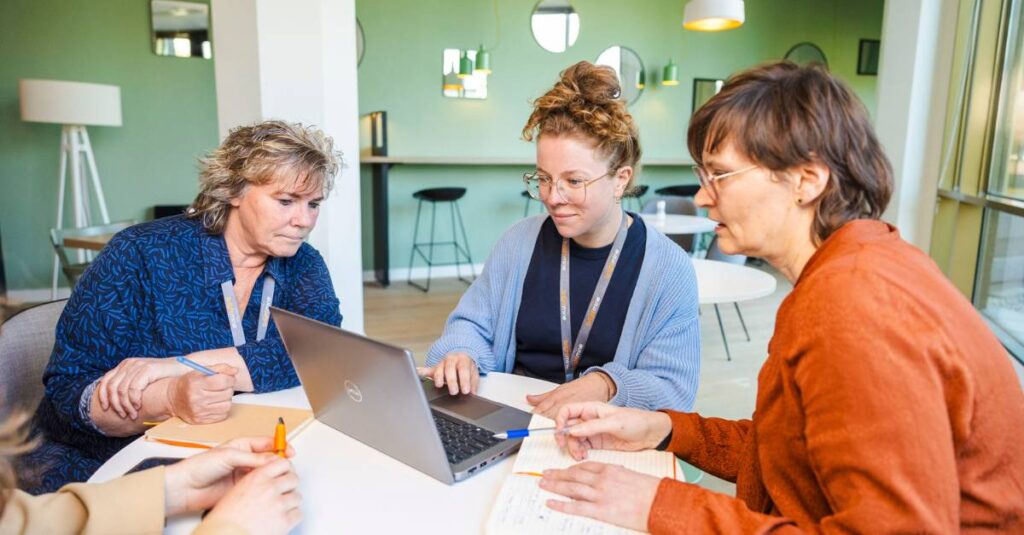 drie werknemers van brightmine die wat bekijken op een laptop